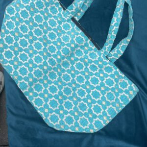 Zahra Turquoise– Handgefertigte Brokattasche in intensivem Türkisblau mit weiß-goldenem Muster, fotografiert auf blauem Samt, Boho Nomad Collection
