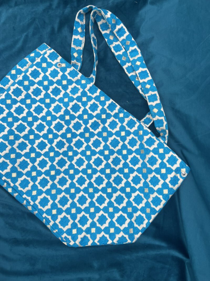 Zahra Pacific – Handgefertigte Brokattasche in intensivem Türkisblau mit weiß-goldenem Muster, fotografiert auf blauem Samt, Boho Nomad Collection