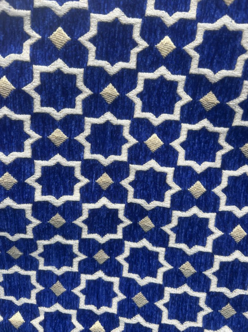 Detailaufnahme des Brokatstoffs der Zahra Royal Tasche: Royalblauer Hintergrund mit orientalischem Sternmuster in Weiß und Gold, handgewebt in Marokko.