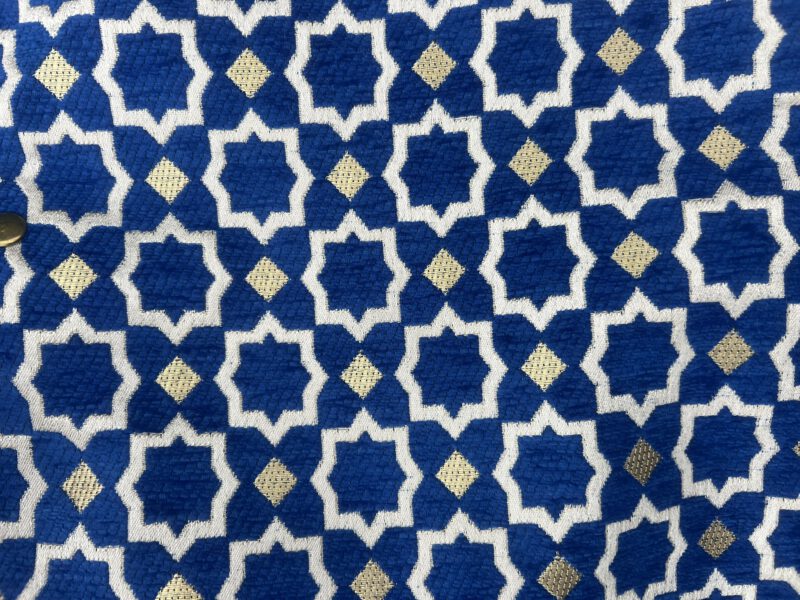 Detailaufnahme des Brokatstoffs der Zahra Océan Tasche: Blauer Hintergrund mit orientalischem Sternmuster in Weiß und Gold, handgewebt in Marokko.