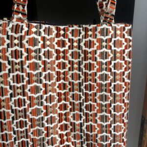 Zahra Nomade – Ausdrucksstarke Brokattasche mit orange-schwarz-goldenem Streifenmuster, fotografiert auf dunklem Stoff, handgefertigt in Marokko