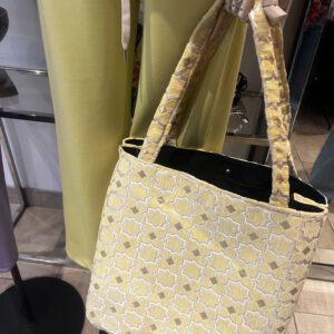 Zahra Citron – Handgefertigte Brokattasche in zartem Gelb mit weiß-goldenem Muster, fotografiert vor gelbem Outfit, Boho Nomad Collection