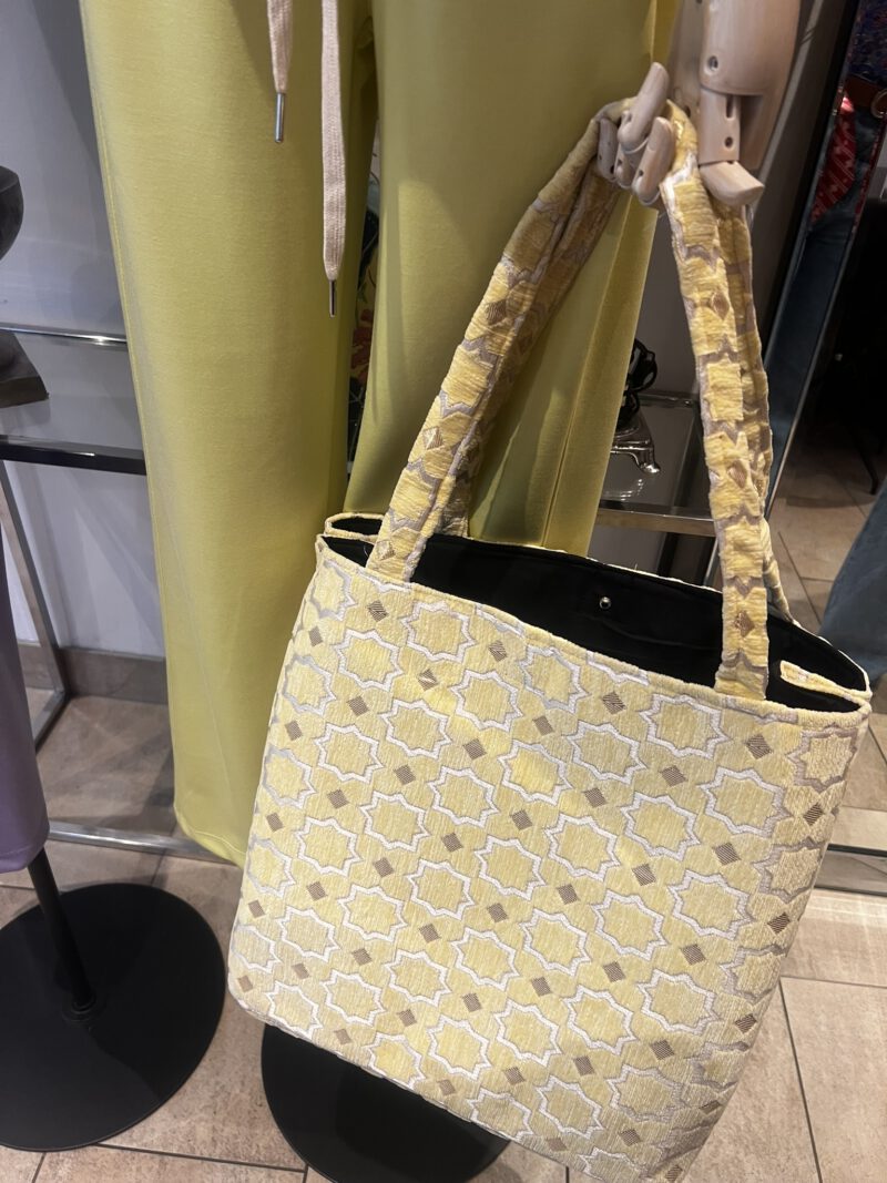 Zahra Citron – Handgefertigte Brokattasche in zartem Gelb mit weiß-goldenem Muster, fotografiert vor gelbem Outfit, Boho Nomad Collection