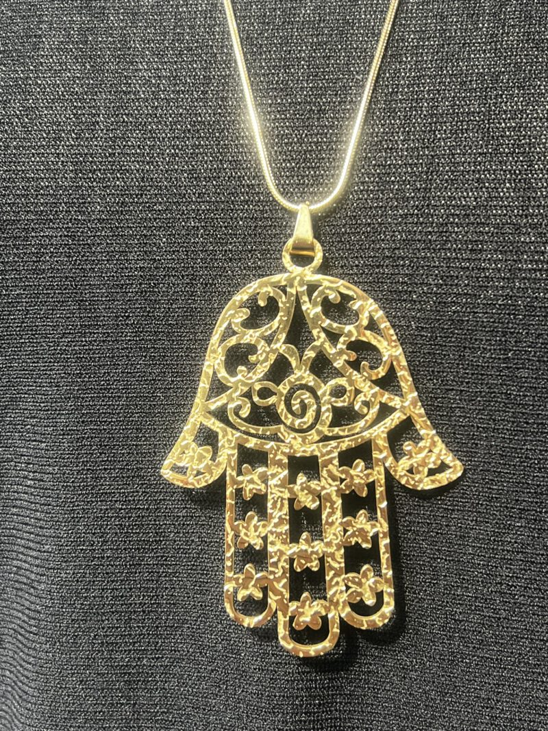 Detailaufnahme der goldfarbenen Hamsa-Kette mit floralen Mustern